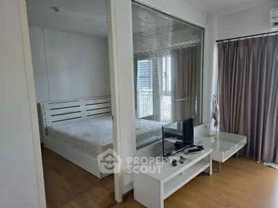 Modern apartment interior with bedroom and living area, featuring sleek furniture and natural light.
