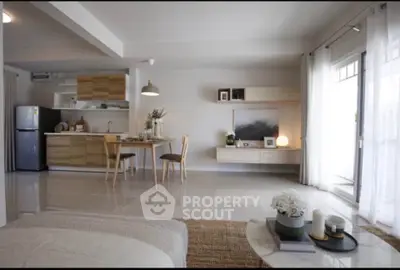 Modern open-plan living room with stylish kitchen and dining area, featuring natural light and contemporary decor.