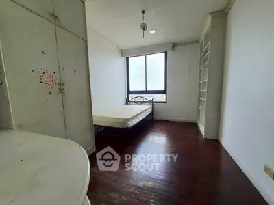 Spacious bedroom with large window and wooden flooring