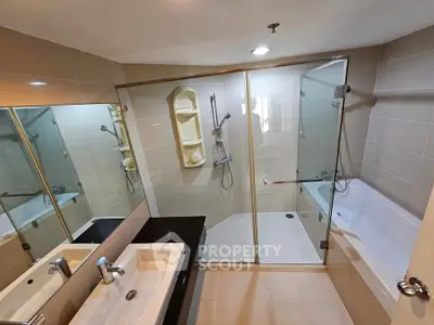Modern bathroom with dual sinks, glass shower, and bathtub in elegant apartment.