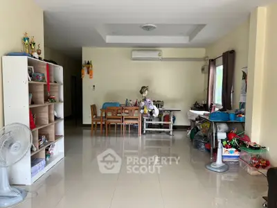 Spacious living room with dining area and air conditioning, featuring tiled floors and ample natural light.