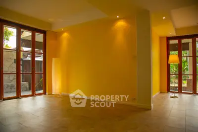 Spacious living room with yellow walls and large windows offering natural light