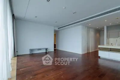 Spacious modern living room with hardwood floors and large windows in luxury apartment.