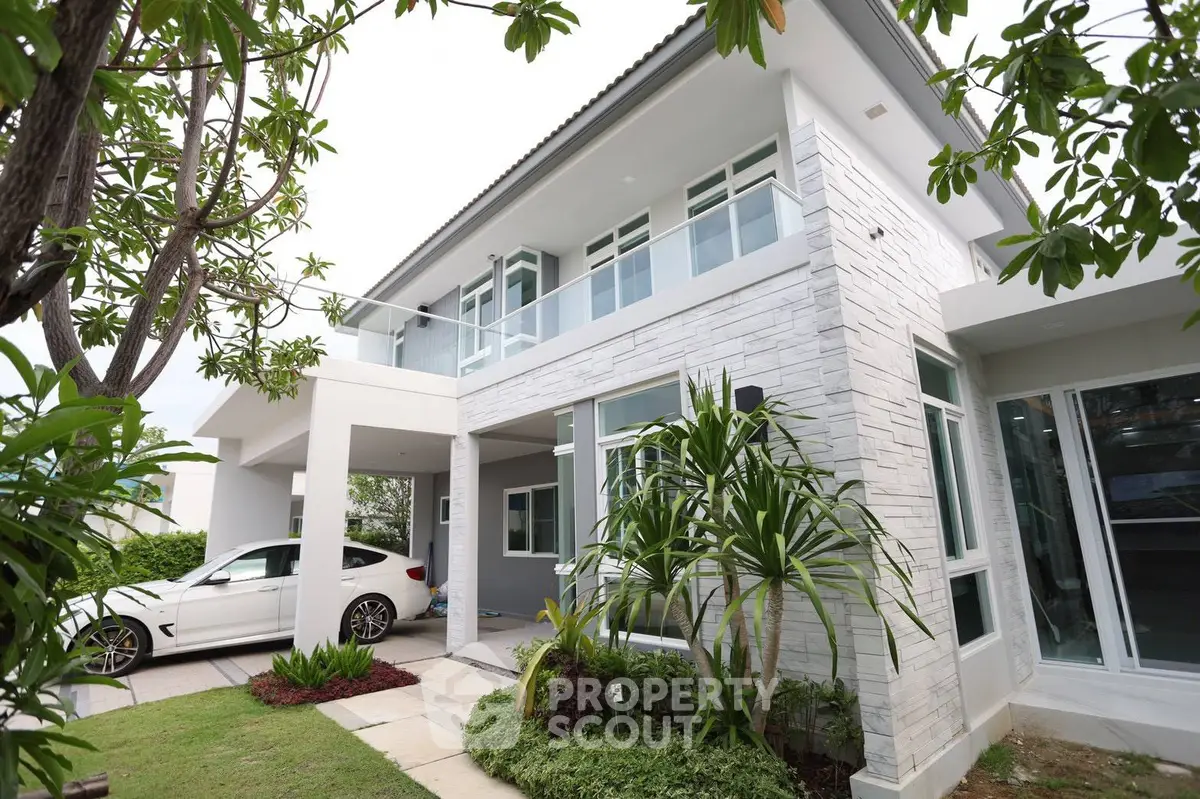 Modern two-story house with sleek design and lush greenery, featuring a spacious driveway and contemporary architecture.