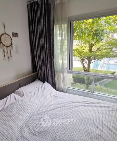 Cozy bedroom with large window overlooking lush garden and pool view