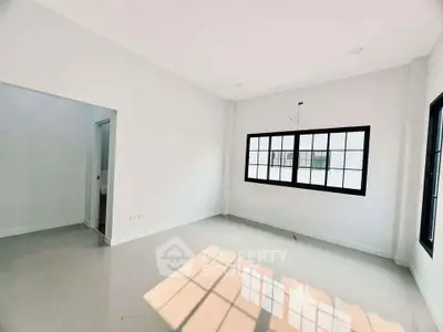 Spacious and bright room with large window and glossy floor tiles.