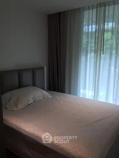 Cozy bedroom with soft lighting and large window, perfect for relaxation.