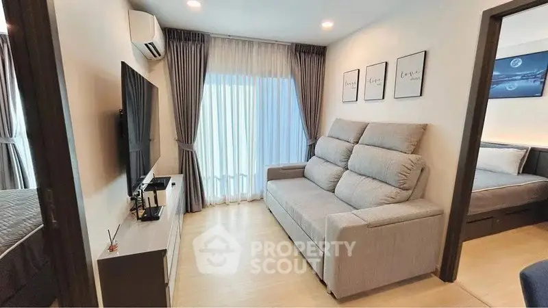 Modern living room with cozy sofa and large TV, adjacent to a stylish bedroom.