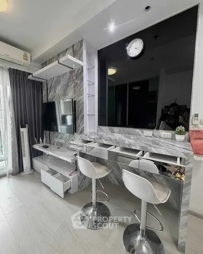 Modern living room with sleek marble accents and stylish bar stools, featuring a wall-mounted TV and elegant decor.