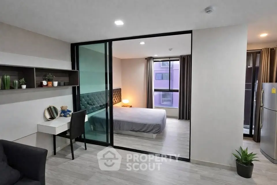 Modern studio apartment with glass partition, cozy bedroom, and sleek decor.