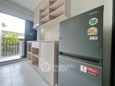 Modern kitchen with open layout and balcony view, featuring sleek appliances and ample storage space.
