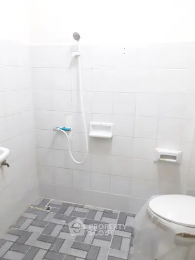 Simple bathroom with white tiles and showerhead, ideal for minimalist design enthusiasts.