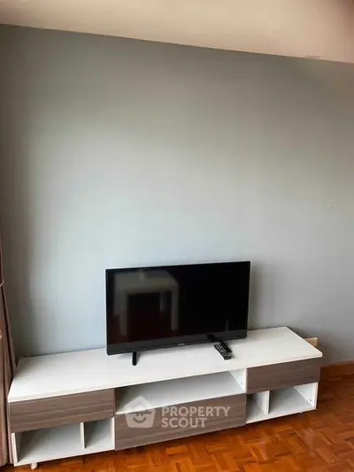 Modern living room with sleek TV stand and flat-screen TV on wooden floor.