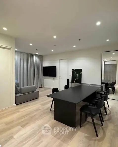 Modern dining area with sleek black table and chairs, adjacent to cozy living space with sofa.