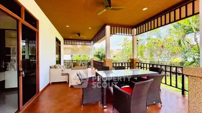 Spacious covered balcony with outdoor dining set and garden view, perfect for relaxation and entertaining.