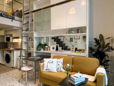 Modern loft-style living room with mezzanine, stylish decor, and open kitchen layout.