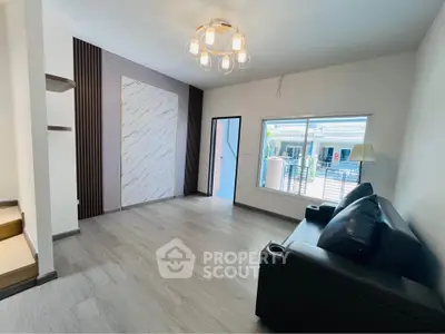 Spacious modern living room with stylish lighting and large window offering natural light.