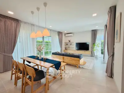 Spacious modern living room with elegant dining area and large windows for natural light.