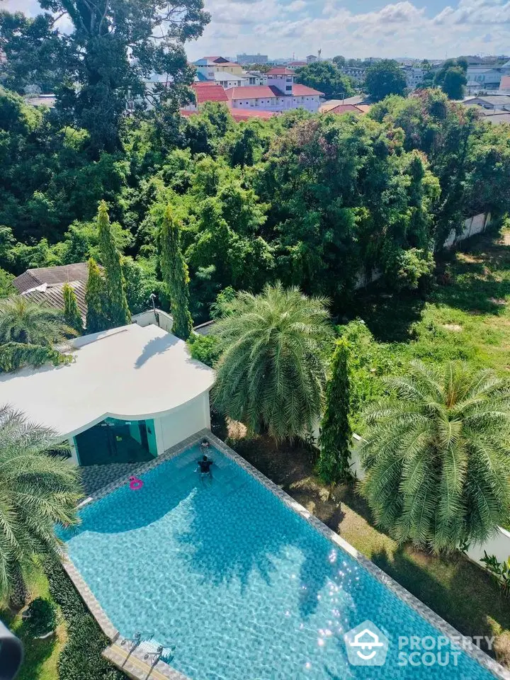 Stunning aerial view of luxurious pool surrounded by lush greenery and modern architecture.