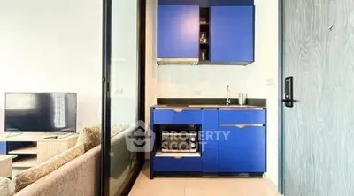 Modern compact kitchen with blue cabinets and sleek appliances in stylish apartment.