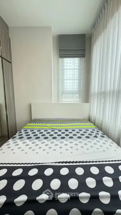 Modern bedroom with stylish polka dot bedding and large windows for natural light.