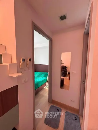 Cozy apartment hallway leading to a bedroom with modern decor and wooden flooring.