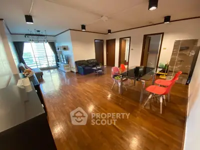 Spacious living room with wooden flooring and modern furniture in a bright apartment.
