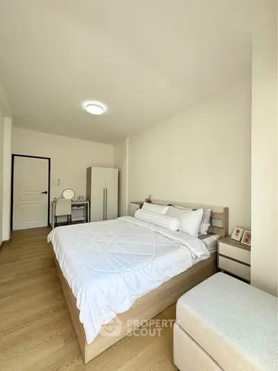 Spacious and bright bedroom with modern furnishings and wooden flooring, perfect for relaxation.