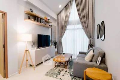 Modern living room with high ceilings, elegant curtains, and stylish furniture.