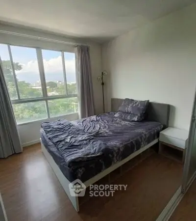Spacious bedroom with large window and scenic view, perfect for relaxation.
