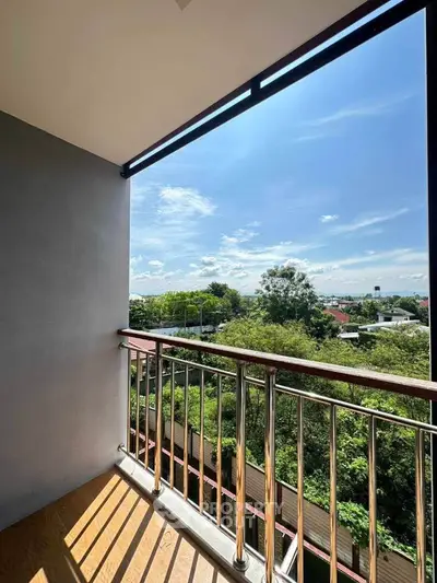 Charming balcony with scenic view of lush greenery and clear blue sky, perfect for relaxation.