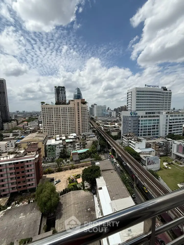 Stunning cityscape view from a high-rise balcony overlooking urban skyline and transportation lines.