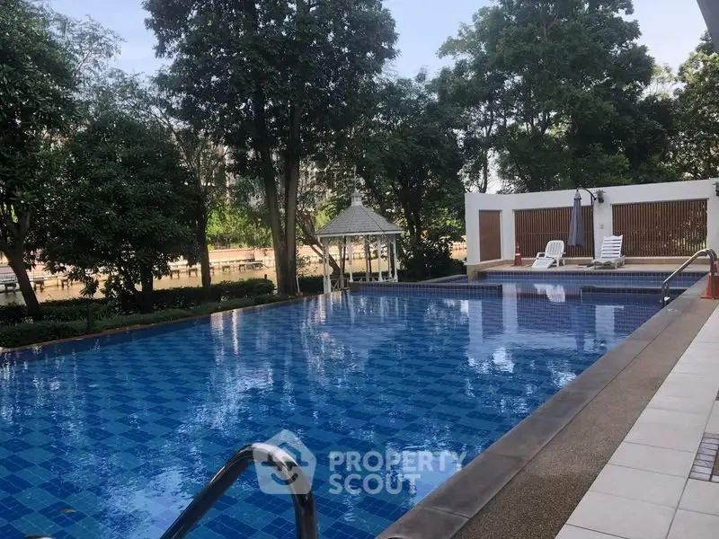 Luxurious outdoor pool surrounded by lush greenery in a serene residential setting.
