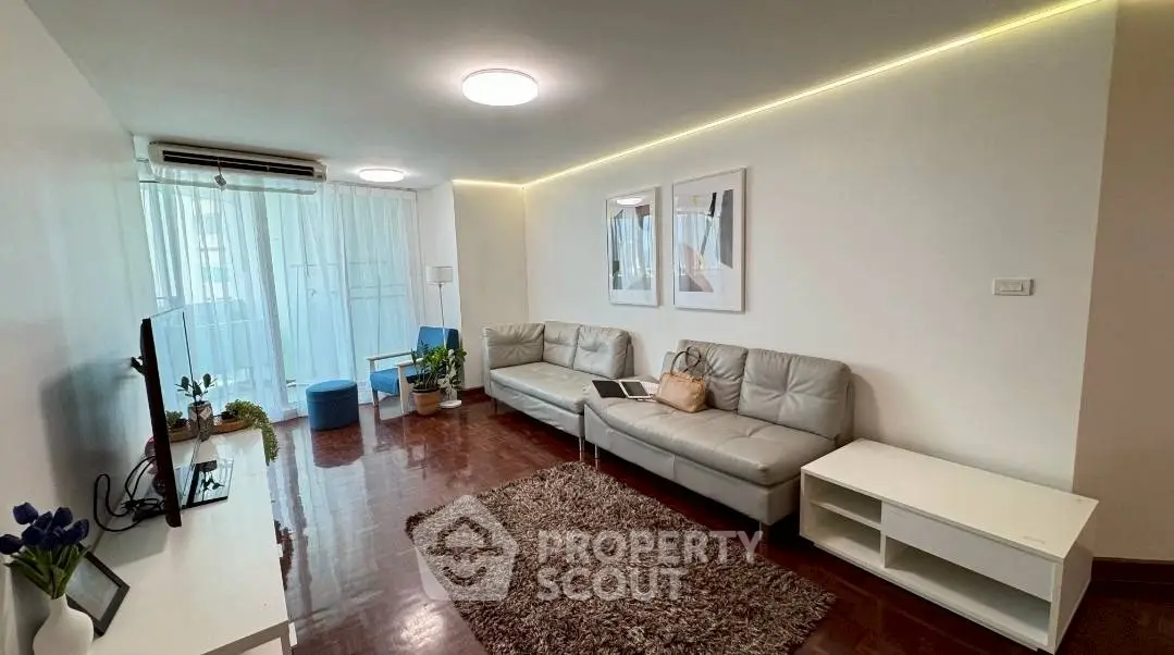 Spacious living room with modern decor and natural light, featuring a cozy sofa and entertainment setup.