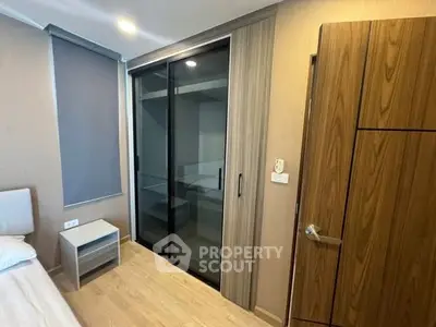 Modern bedroom with sleek sliding closet doors and wooden accents.