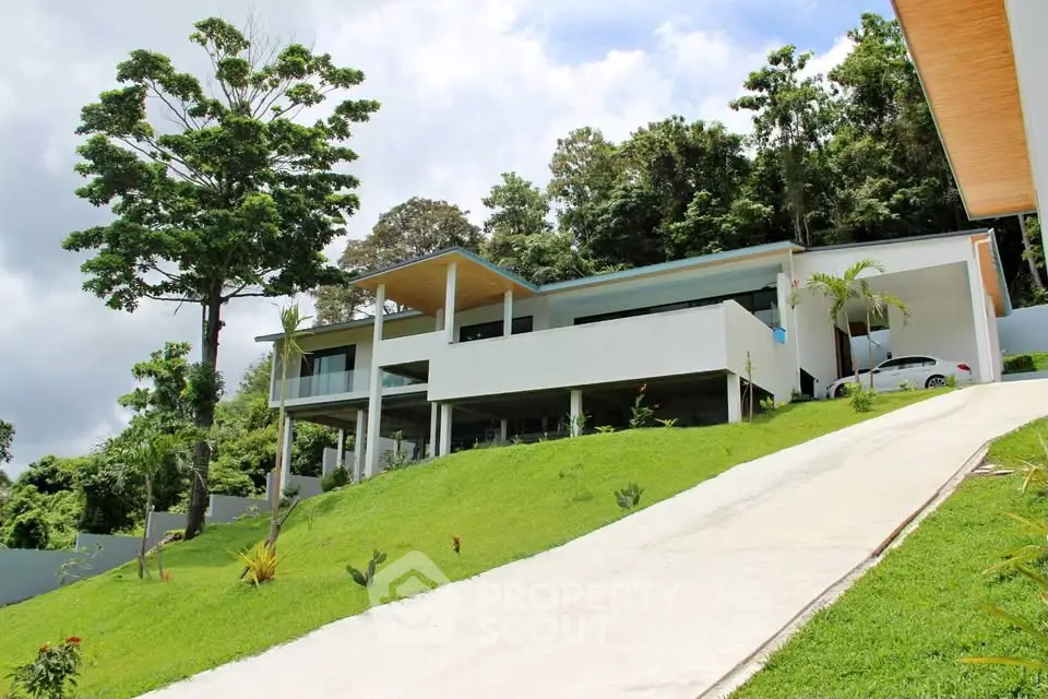 Stunning modern hillside home with lush greenery and sleek architecture.