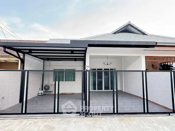 Modern single-story house with gated entrance and spacious driveway.