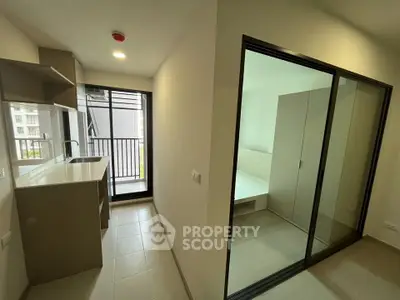 Modern apartment with sleek kitchen and sliding glass doors to bedroom and balcony.