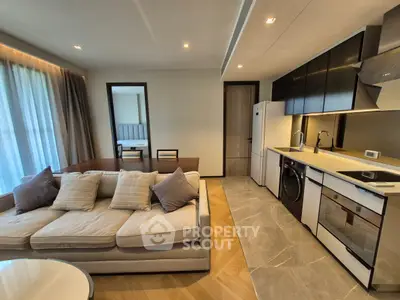 Modern open-layout living room with kitchen, featuring sleek appliances and stylish decor.