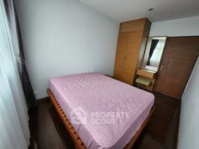 Spacious bedroom with wooden flooring and large window for natural light.
