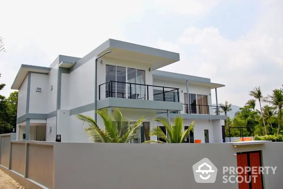 Modern luxury villa with sleek design and spacious balcony in tropical setting.