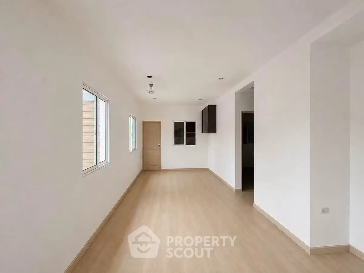 Spacious empty room with wooden flooring and natural light, perfect for customization.