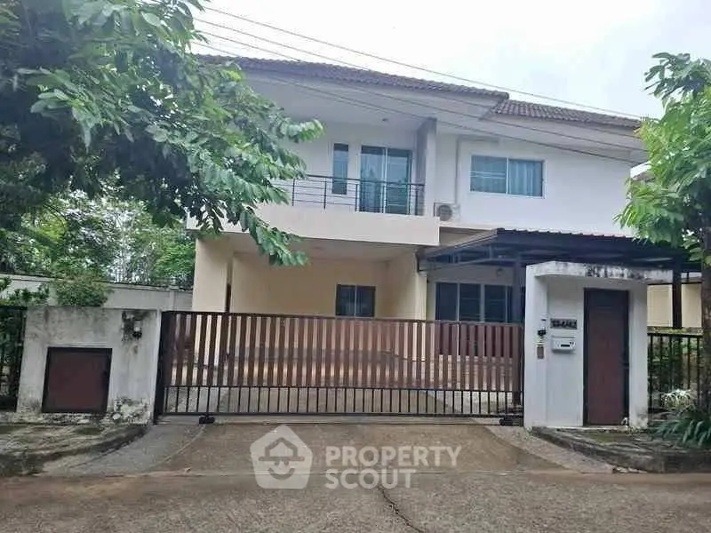 Charming two-story house with gated entrance and lush greenery, perfect for family living.