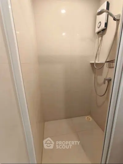 Modern shower area with sleek tiles and water heater in a compact bathroom.