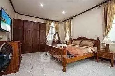 Spacious bedroom with elegant wooden furniture and ample natural light.