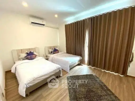 Spacious bedroom with two beds and elegant curtains, perfect for comfort and relaxation.