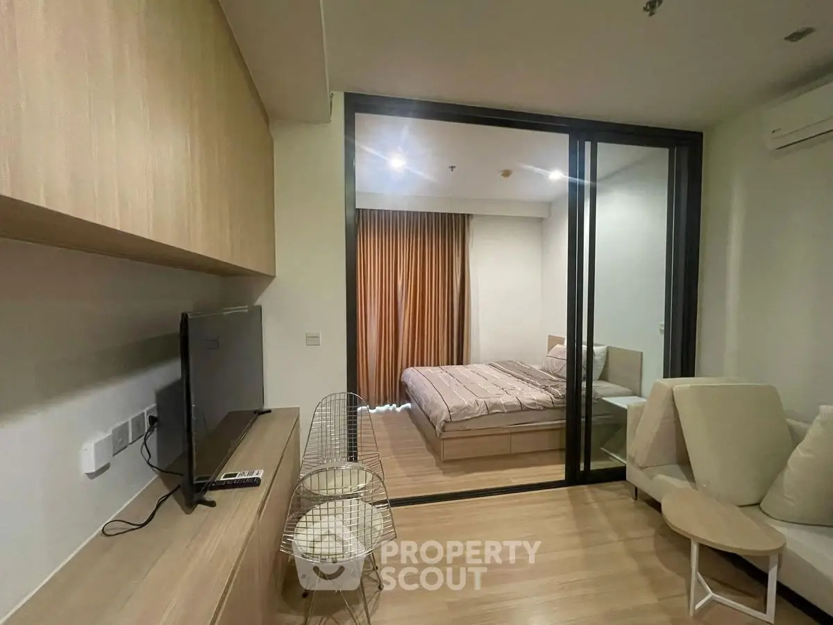Modern studio apartment with glass partition, cozy living area, and stylish bedroom.