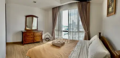 Spacious bedroom with large windows offering ample natural light and a serene view, complemented by elegant drapery and classic wooden furniture.