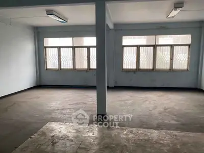 Spacious empty room with large windows and natural light, ideal for office or studio space.