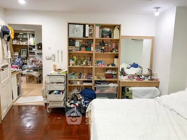 Cozy bedroom with wooden flooring and organized shelves in a modern apartment.